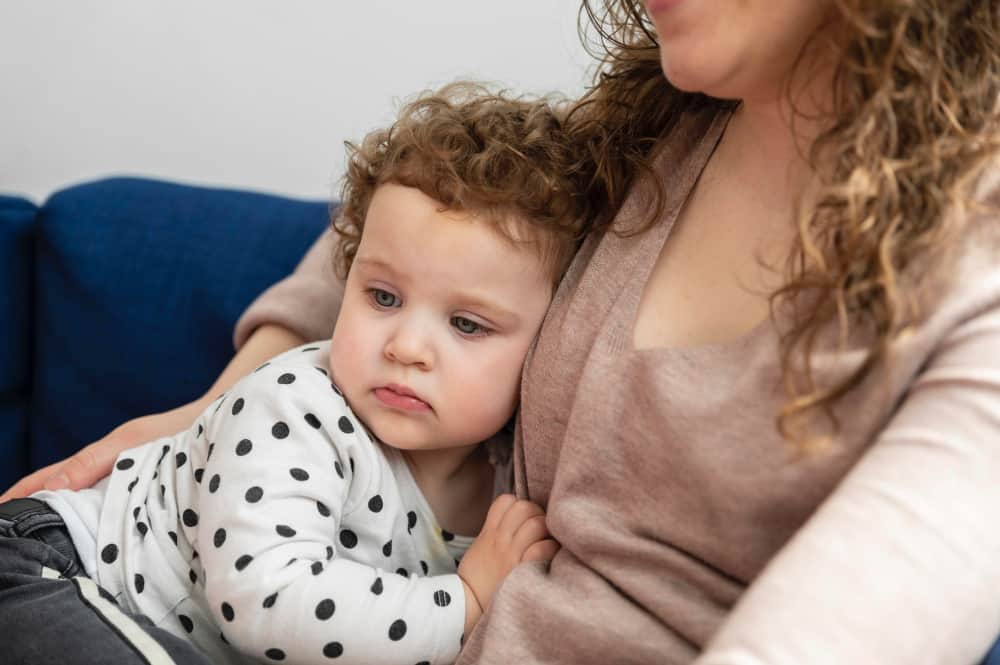 Baby holding a parent's hand at bedtime