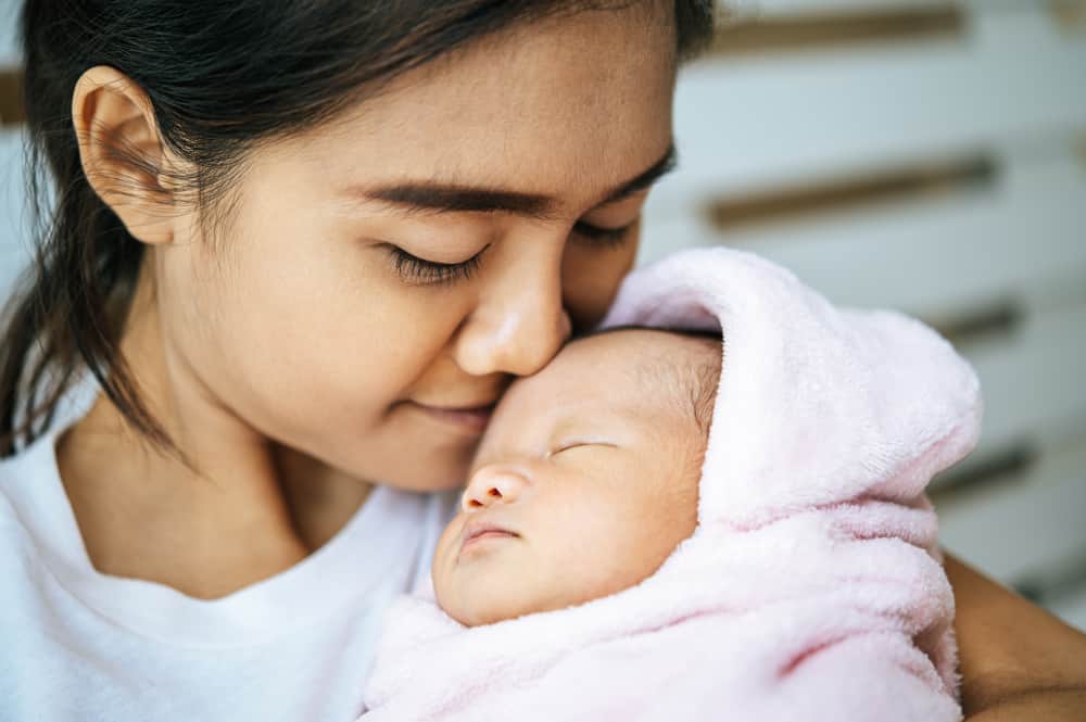 Parent giving a gentle bath to a newborn baby in a warm, cozy setting