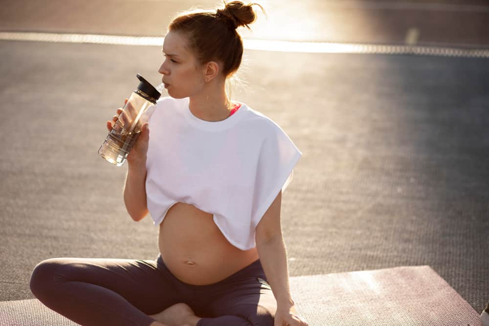 Pregnant woman holding a water bottle, symbolizing hydration and wellness