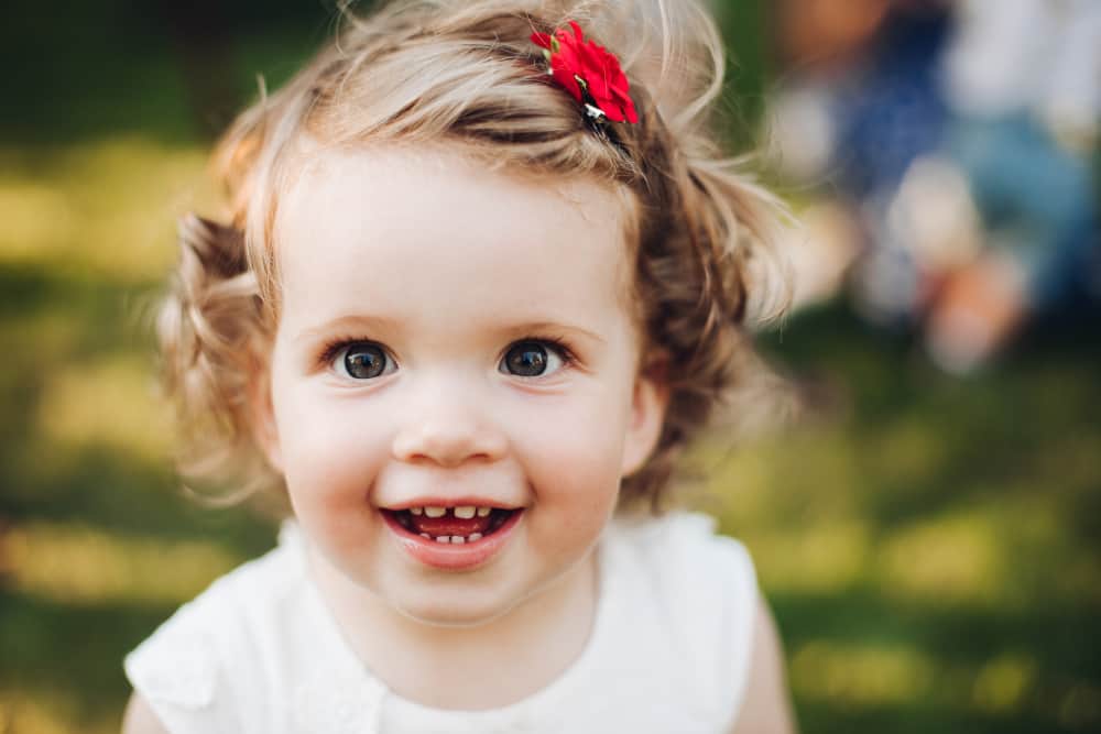 Baby chewing on a teething toy while drooling and smiling