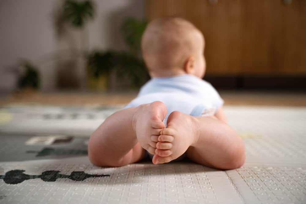 Smiling baby enjoying tummy time on a play mat with toys