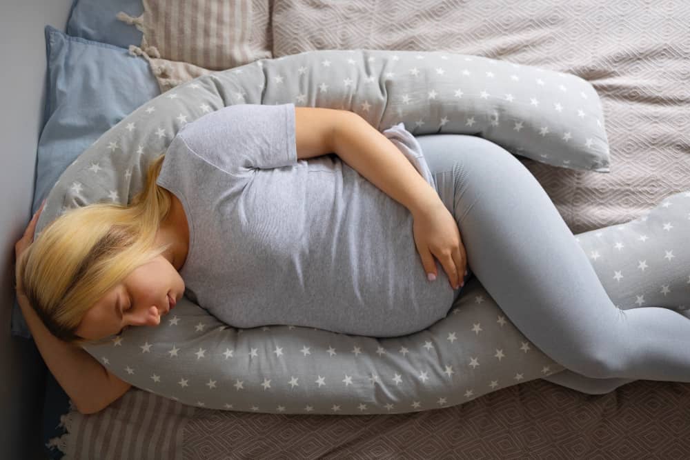 Pregnant person resting comfortably on side with pillows for support