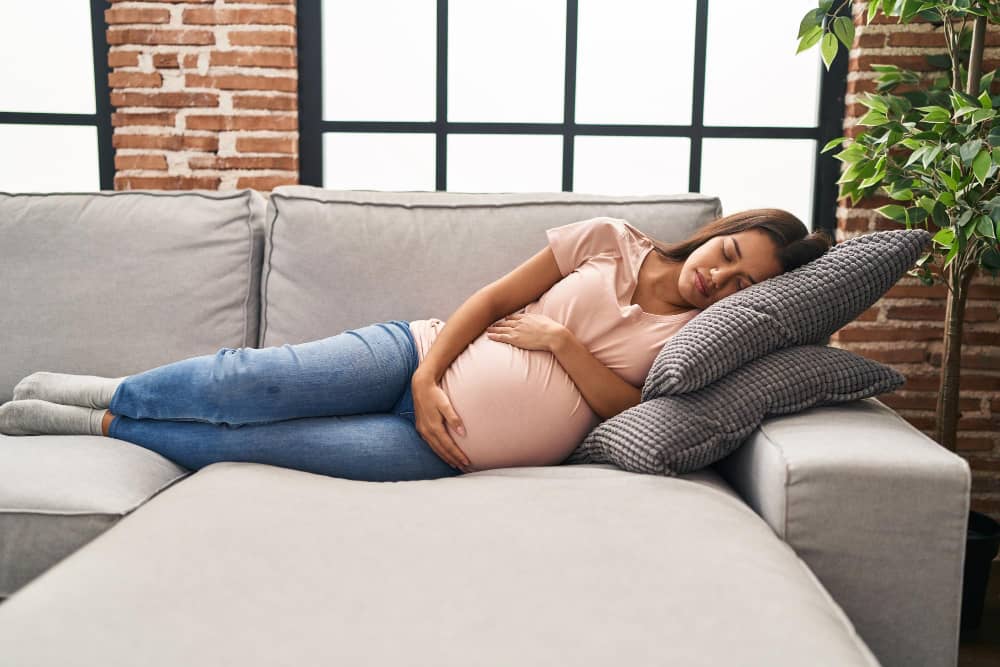 Pregnant woman resting on a couch with soft natural light