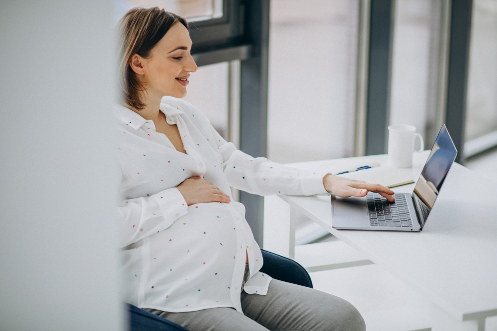 Pregnant woman working at a desk looking focused but slightly stressed
